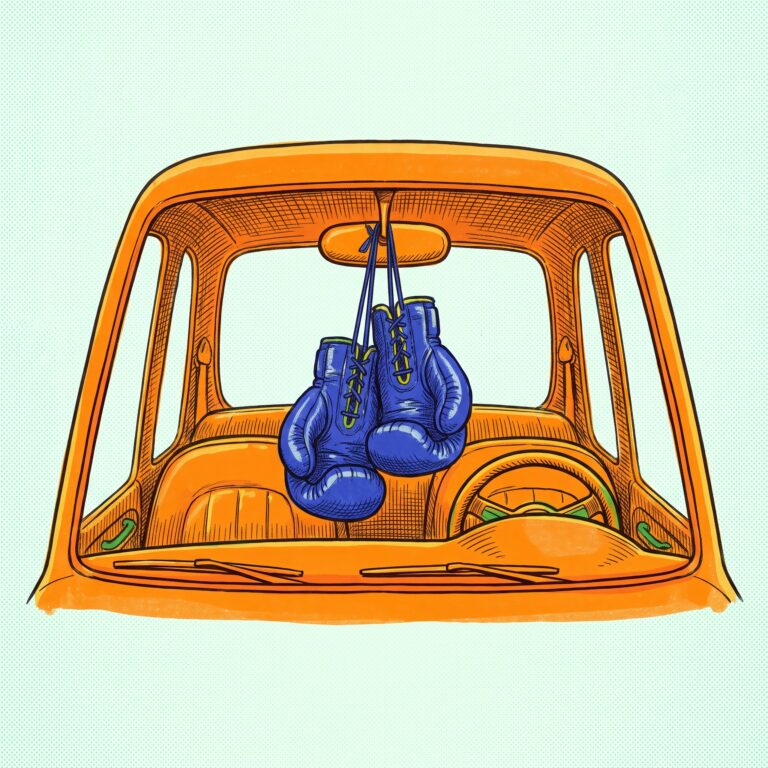 A pair of boxing gloves hanging from the rear-view mirror of a car.